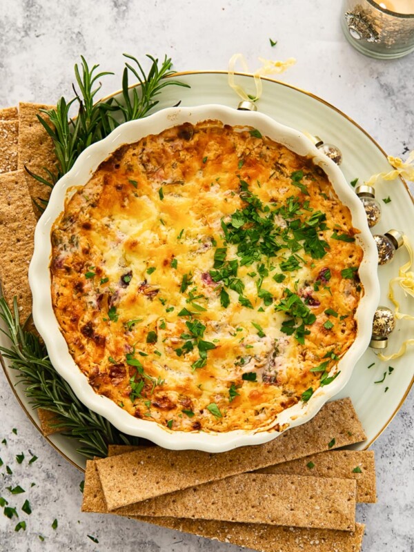 top down view of cheesy dip with chorizo and cranberries, cracker next to the dish