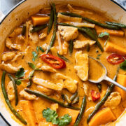 Thai red curry with chicken, sweet potatoes and green beans in a white pan