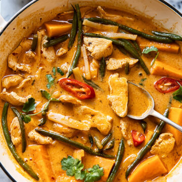 Thai red curry with chicken, sweet potatoes and green beans in a white pan