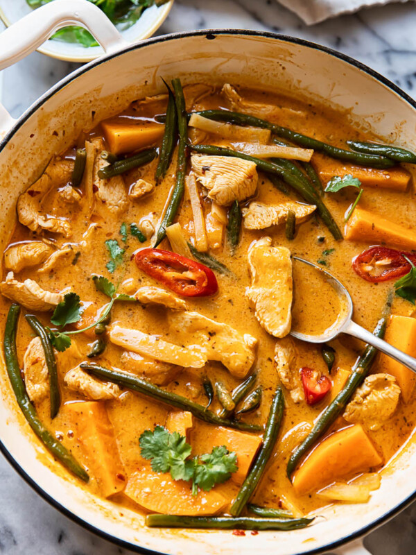 Thai red curry with chicken, sweet potatoes and green beans in a white pan