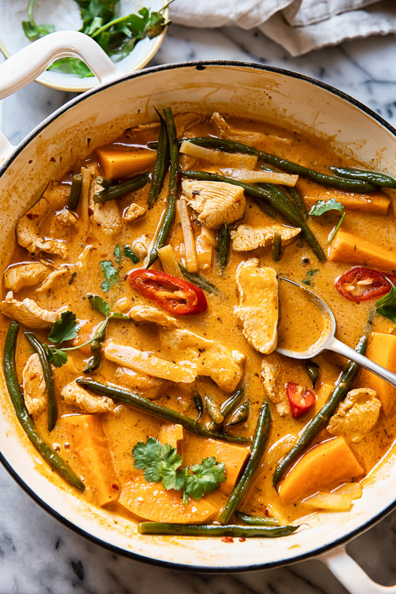 Thai red curry with chicken, sweet potatoes and green beans in a white pan