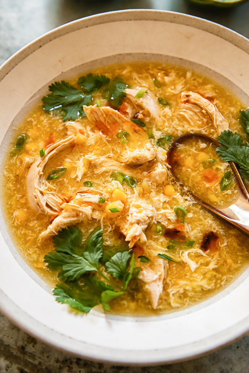 chicken and corn soup in a bowl topped with fresh coriander leaves