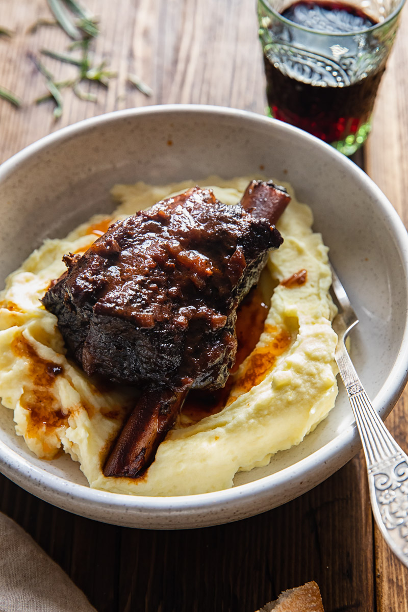 braised short rib on mashed potatoes in a bowl, glass of red wine