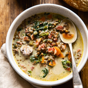 top down view of a bowl of soup and a loaf of bread on a table