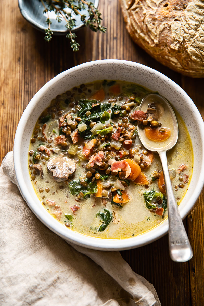 top down view of a bowl of soup and a loaf of bread on a table