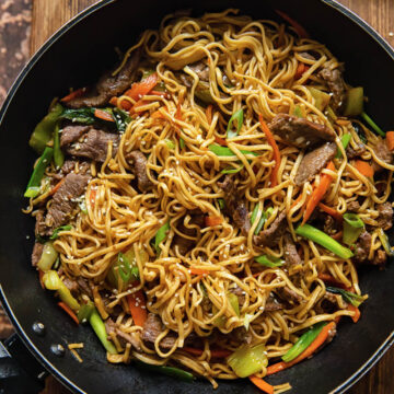 top down view of Asian noodles dish with beef and vegetables in a wok