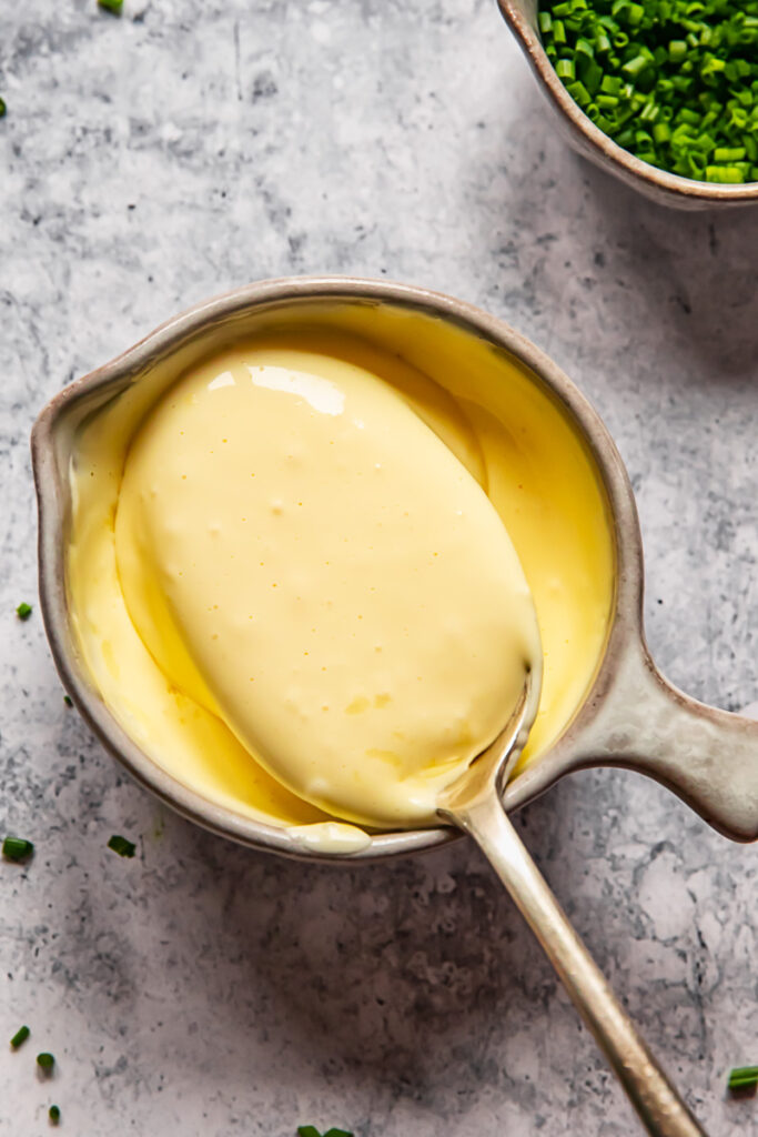 hollandaise sauce in a cup with a spoon in it