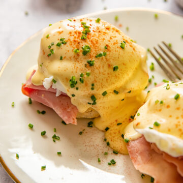 eggs benedict sprinkled with chives on a white plate