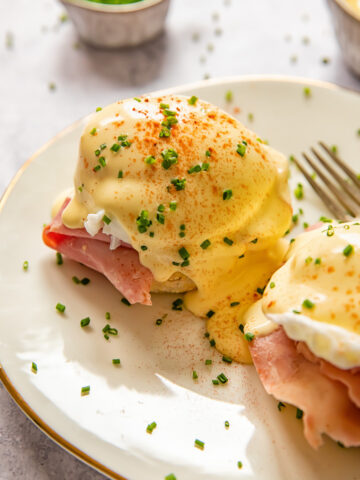 eggs benedict sprinkled with chives on a white plate