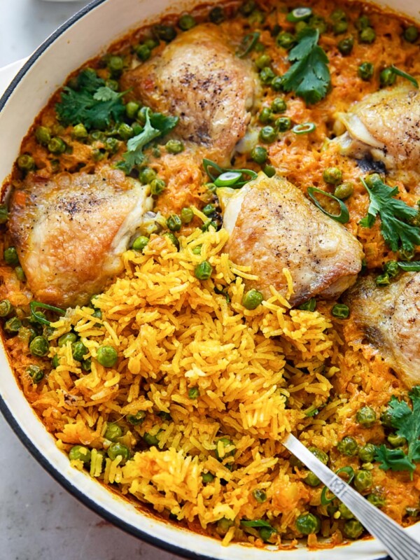 top down view of chicken thigh and yellow turmeric rice casserole with green peas