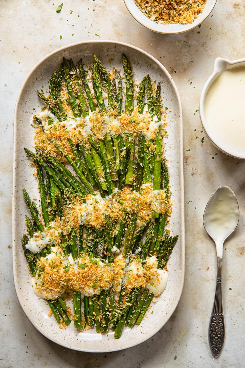 top down view of roasted asparagus with cheese sauce and breadcrumbs