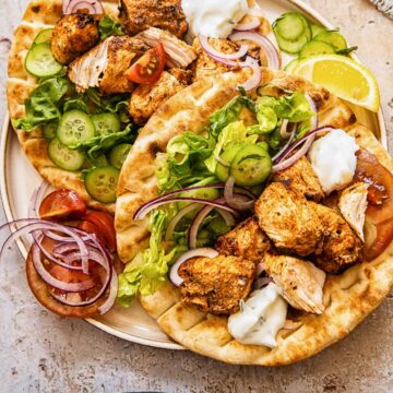 top down view of chicken kebabs on top of flatbreads on a plate