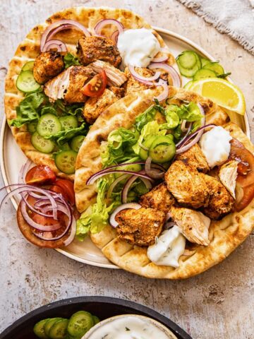 top down view of chicken kebabs on top of flatbreads on a plate