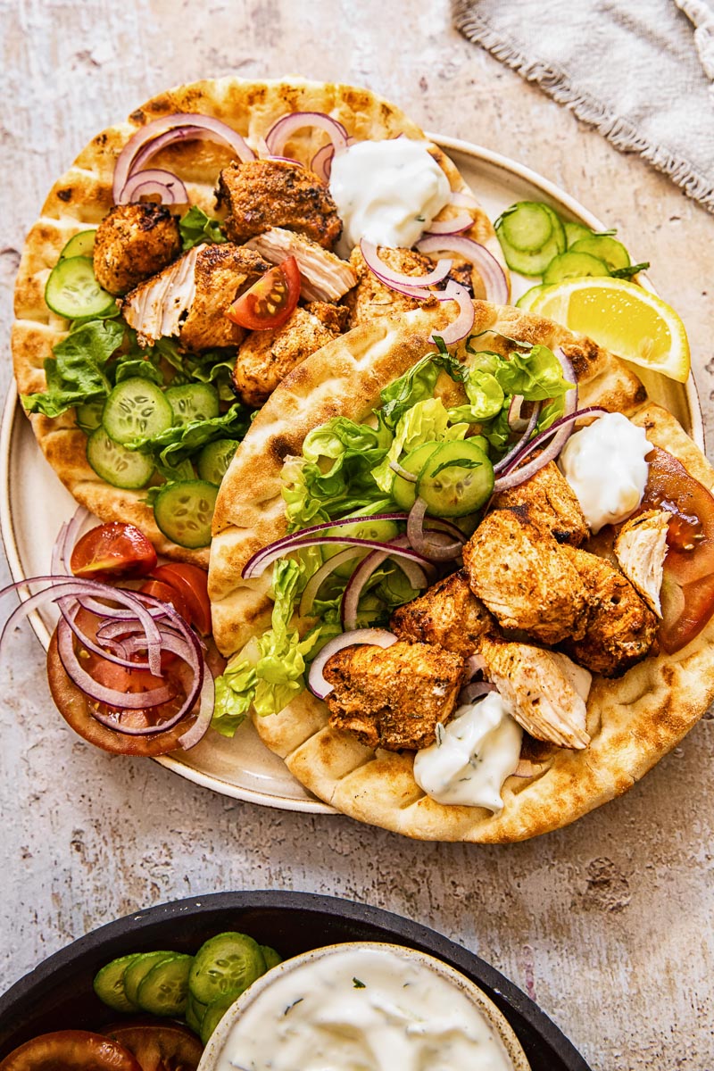 top down view of chicken kebabs on top of flatbreads on a plate