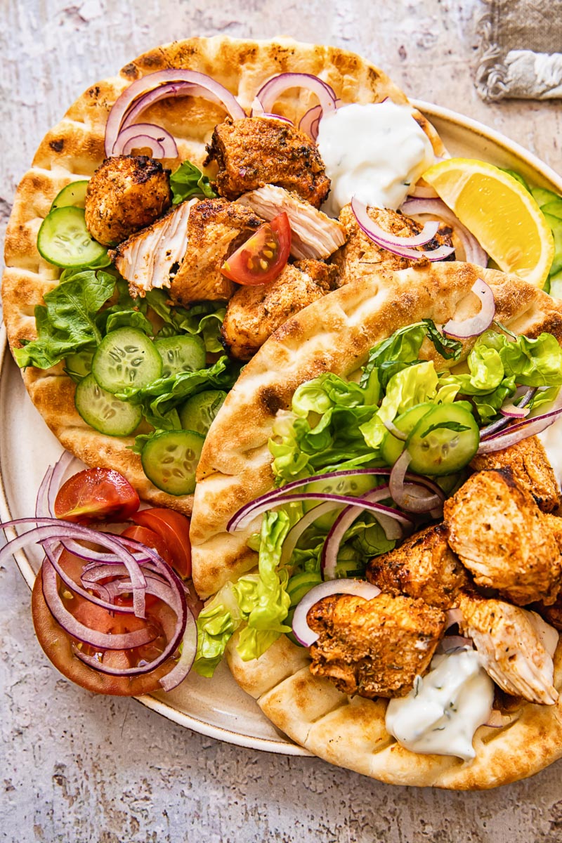 top down view of chicken kebabs with topping on pitas