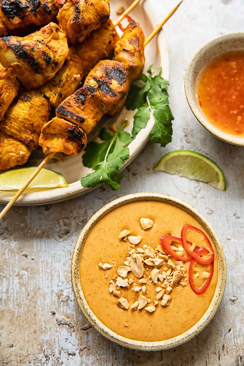 top down view of chicken satay and peanut sauce in a small bowl