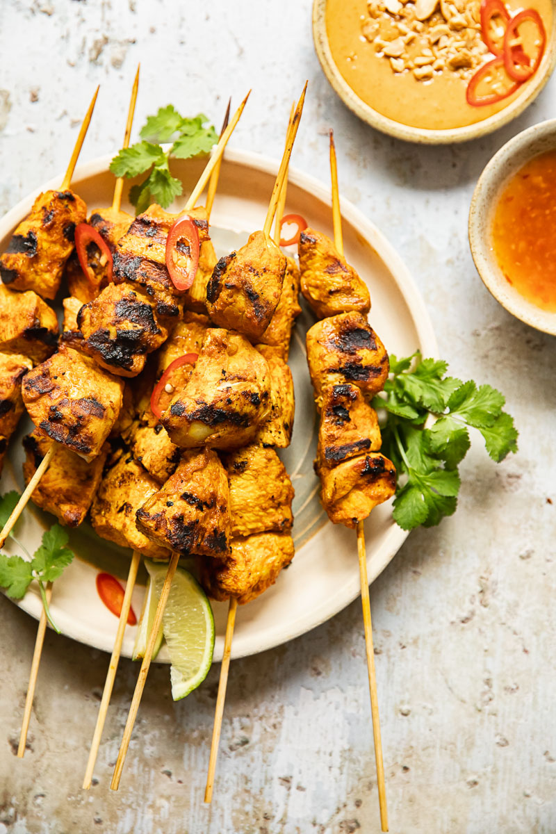 top down view of chicken satay with peanut sauce and red chilli sauce