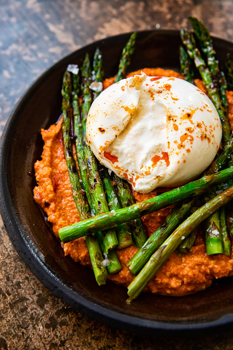 close up of grilled asparagus with romesco sauce and burrata