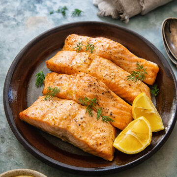 top down view of salmon on a plate, lemon dill sauce and a napkin