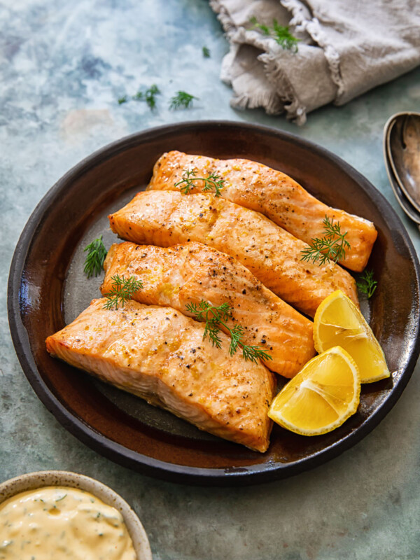 top down view of salmon on a plate, lemon dill sauce and a napkin