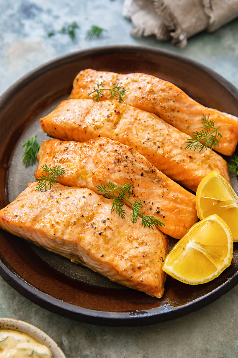 pieces of cooked salmon with lemon wedges on a plate