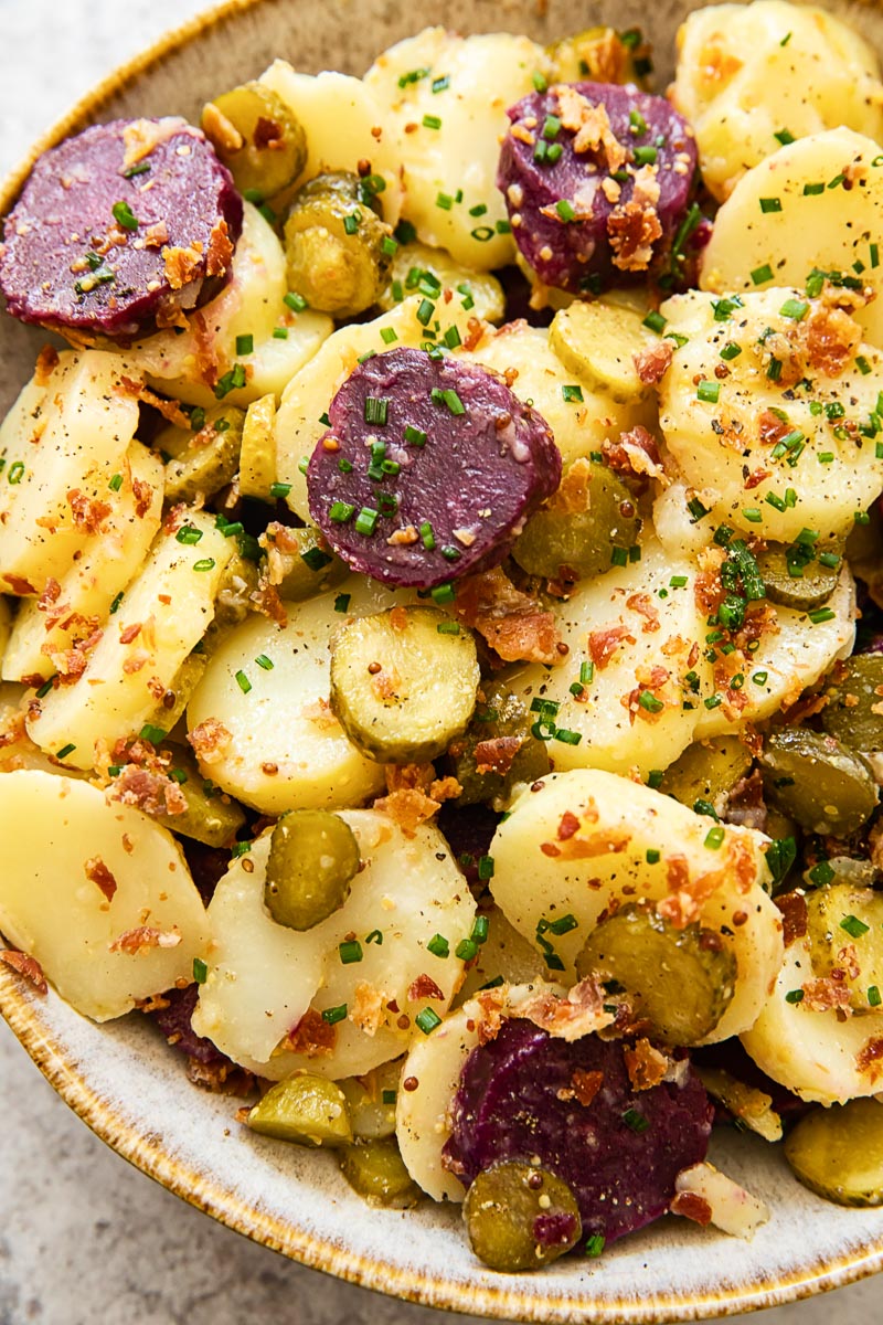 close up of potato salad with pickles and bacon
