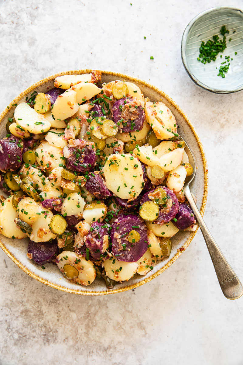 white and purple potato salad in a bowl with a spoon in it