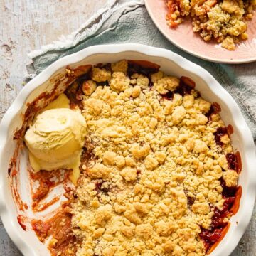 top down view of rhubarb crumble with vanilla ice cream in a pan and on a pink plate