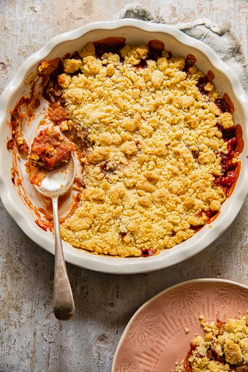 fruit crumble in a round pie dish with a serving spoon in it