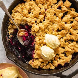 top down view of apple blackberry crumble in a pan topped with two scoops of vanilla ice cream