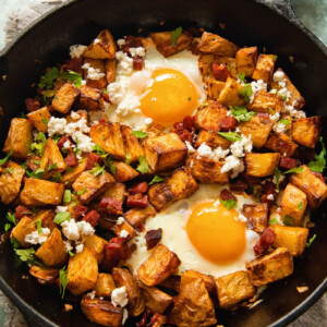 top down view of a skillet with diced potatoes, chorizo and egg with feta