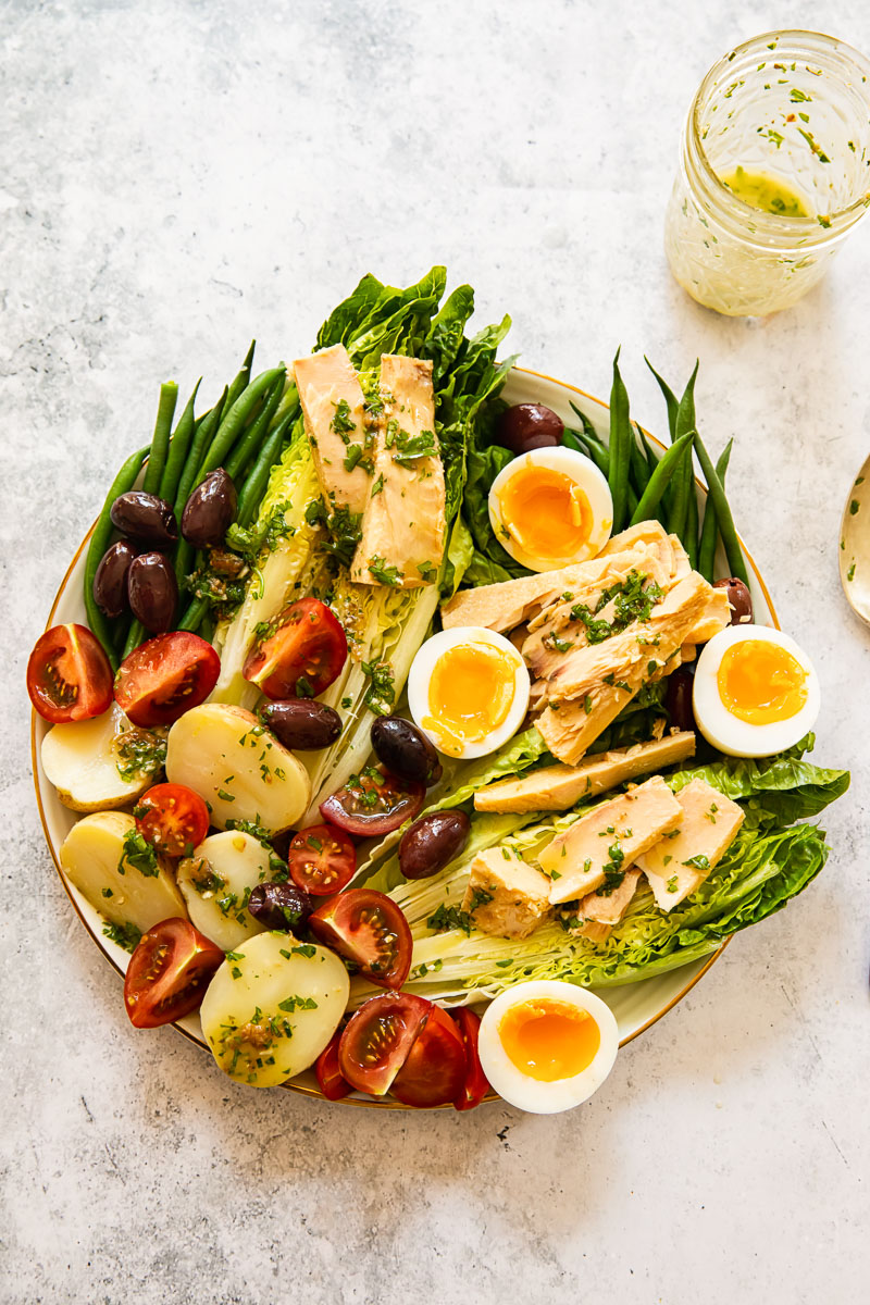 top down view of Salade Nicoise with a vinaigrette next to it