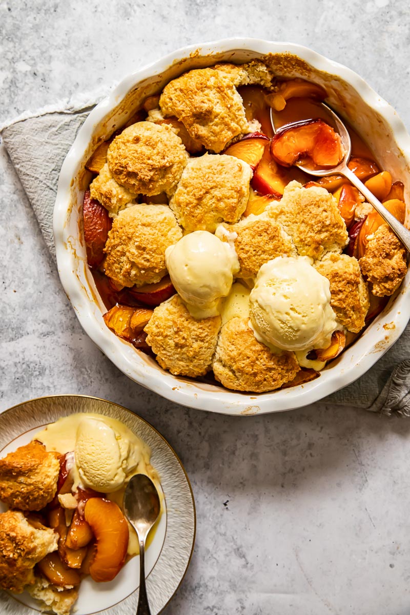 top down view of peach cobbler topped with two ice cream scoops