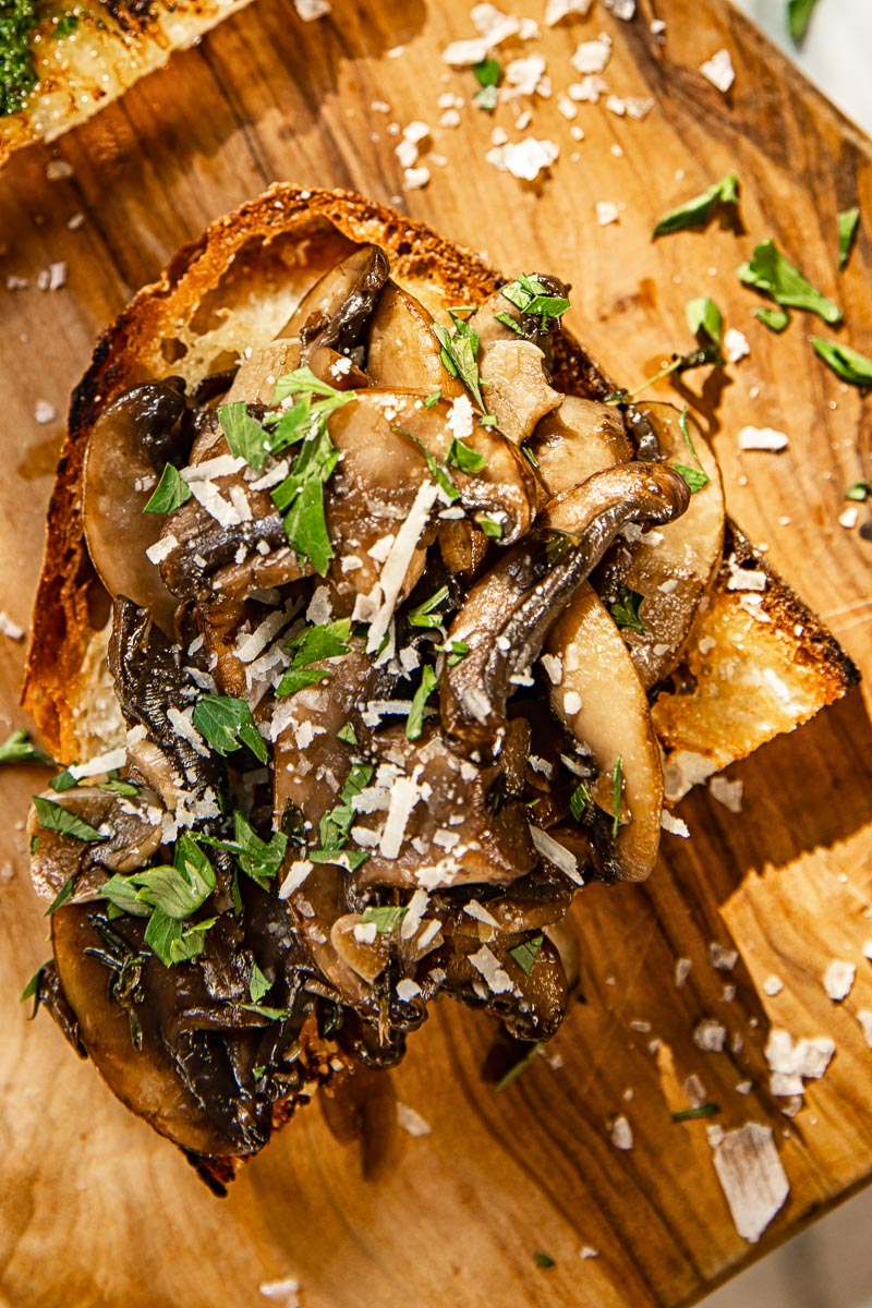 top down view of crostini topped with mushrooms, parsley and Pecorino Romano