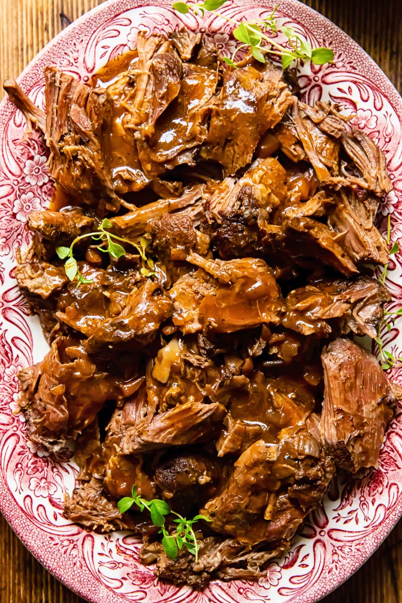 shredded lamb on a platter with gravy on top