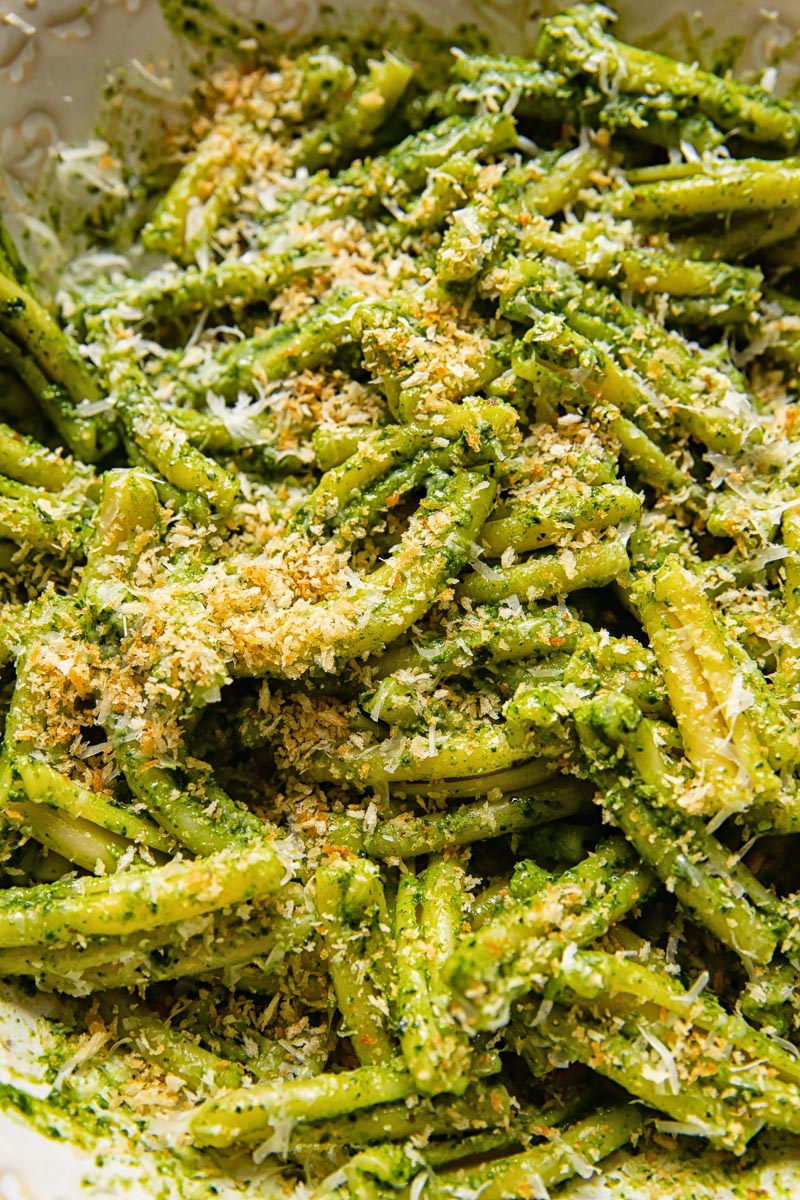 close up of pesto pasta covered with breadcrumbs