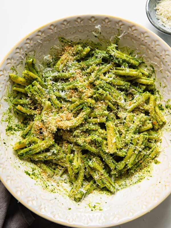 pesto pasta in a serving bowl with grated parmesan next to it