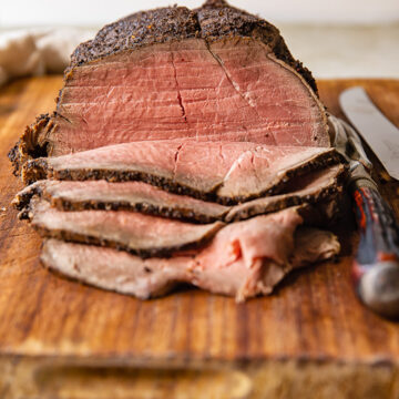slices of roast beef and whole beef jointon cutting board
