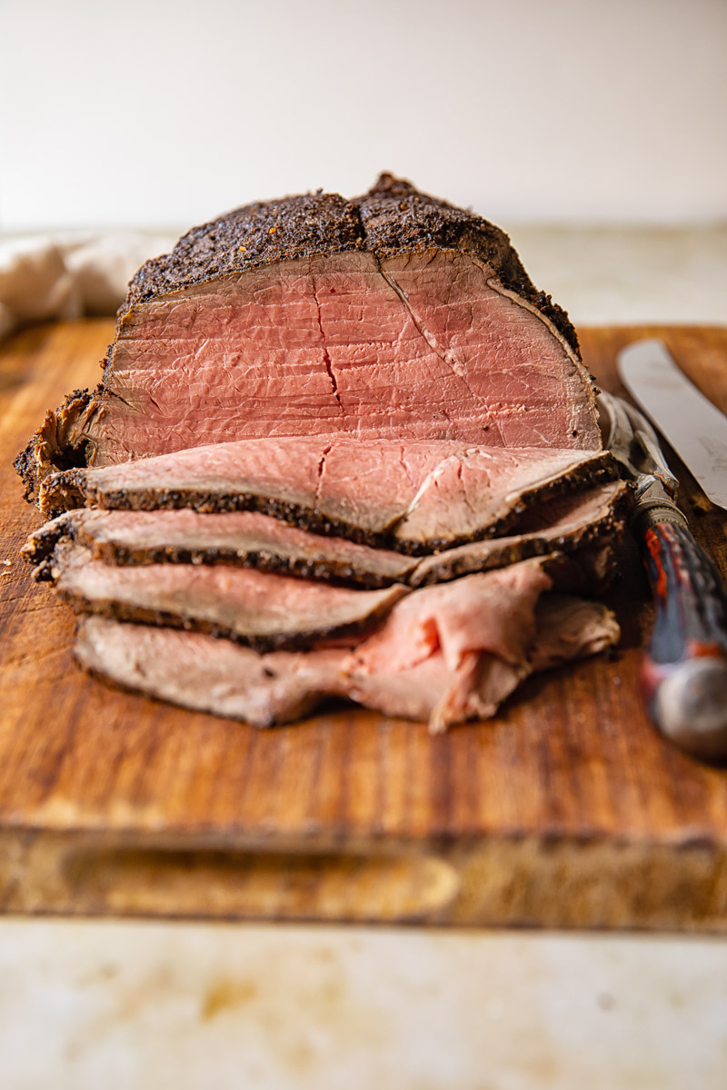 slices of roast beef and whole beef jointon cutting board