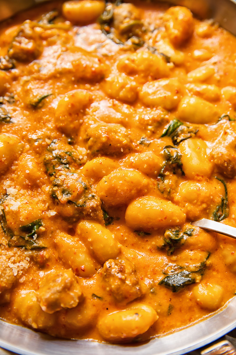 close up of gnocchi in red sauce with sausages