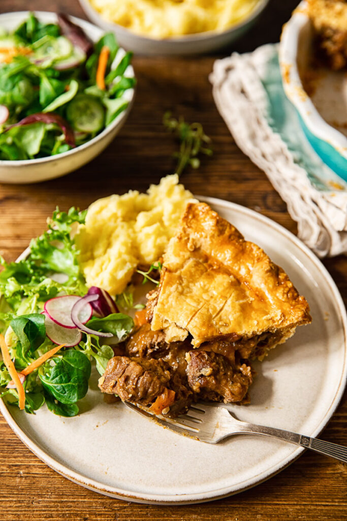 Plate with steak and ale pie, potatoes and salad