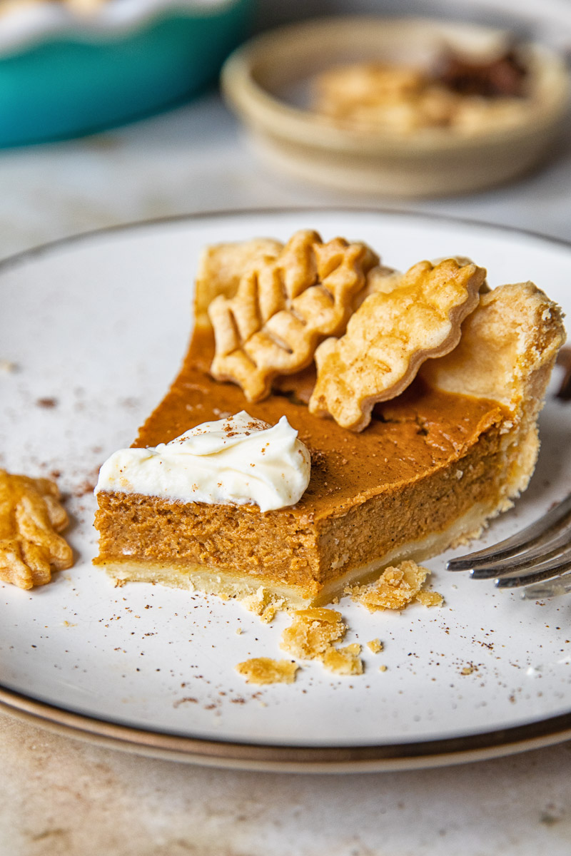 a slice of pumpkin pie on a plate with a bite taken out