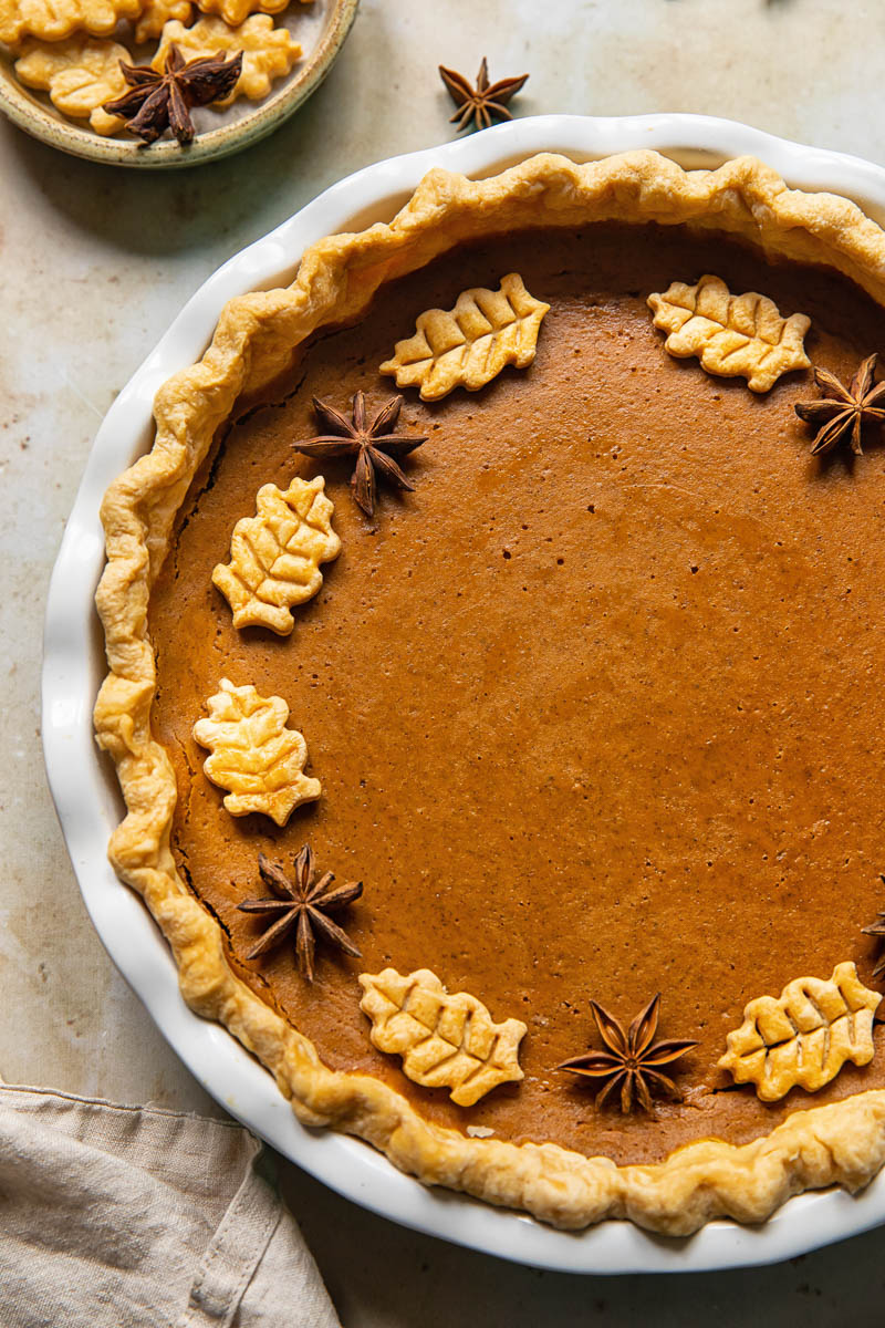 top down view of pumpkin pie decorated with pastry leaves and star anise