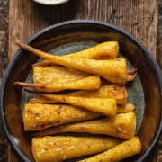 top down view of roasted parsnips on a plate on wooden background