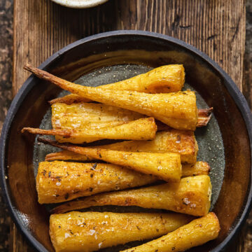 top down view of roasted parsnips on a plate on wooden background