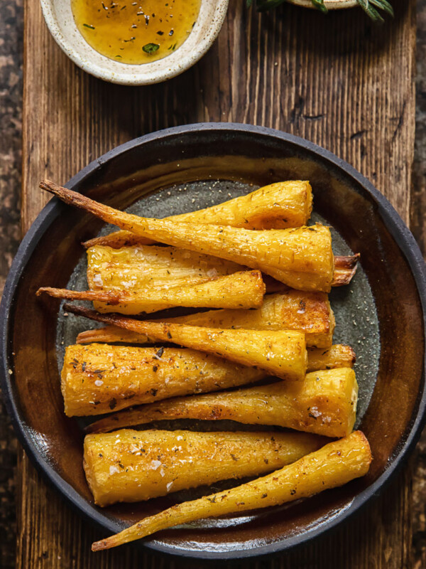 top down view of roasted parsnips on a plate on wooden background