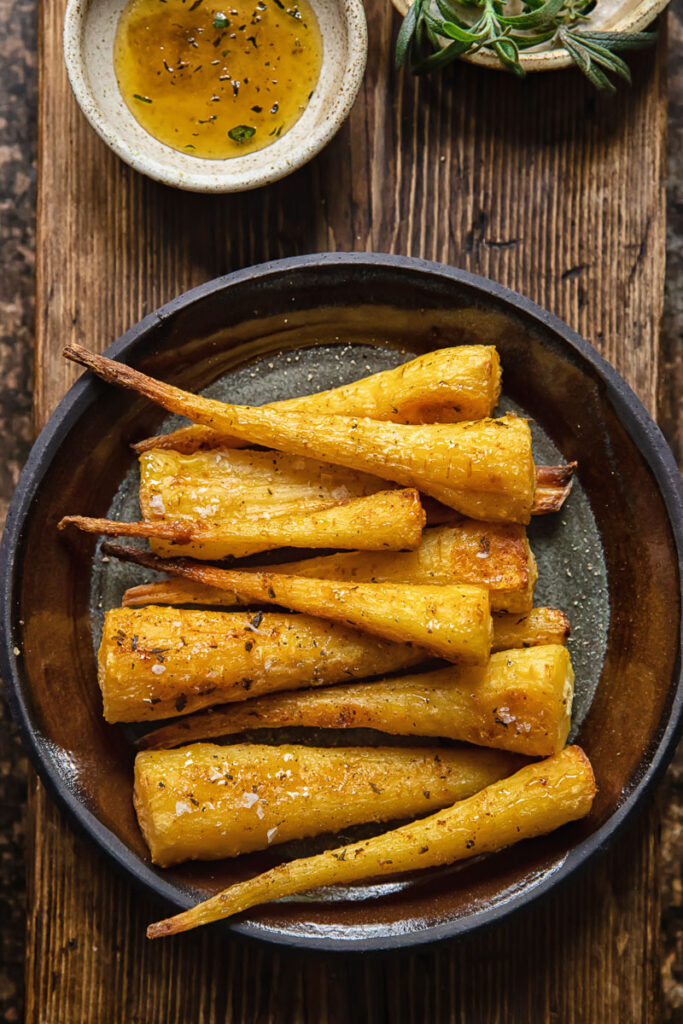 top down view of roasted parsnips on a plate on wooden background