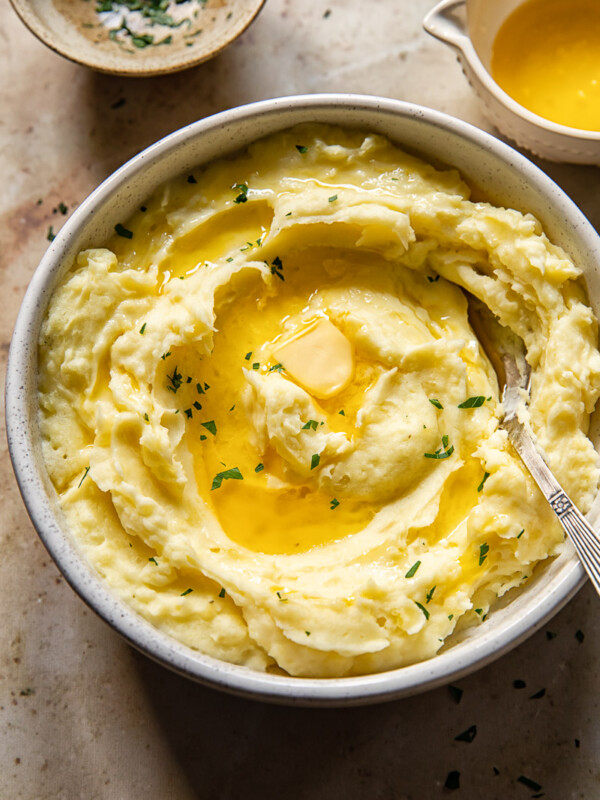 top down view of mashed potatoes drizzled with melted butter and chopped parsley in a bowl