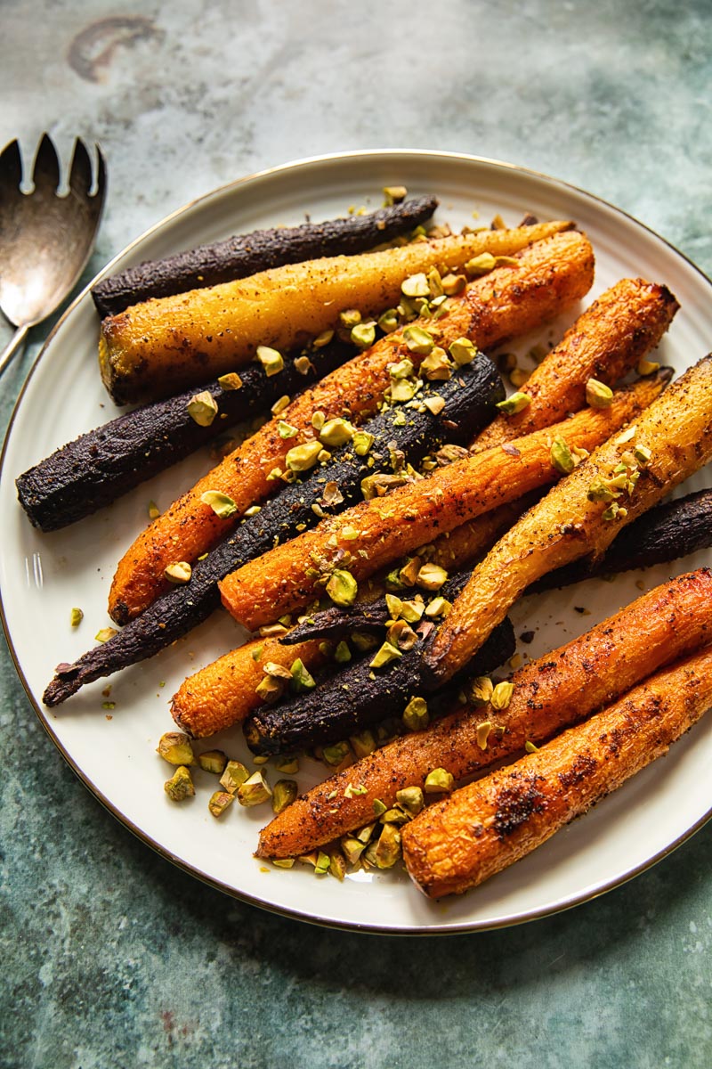 top down view of cooked carrots with pistachios on a white platter