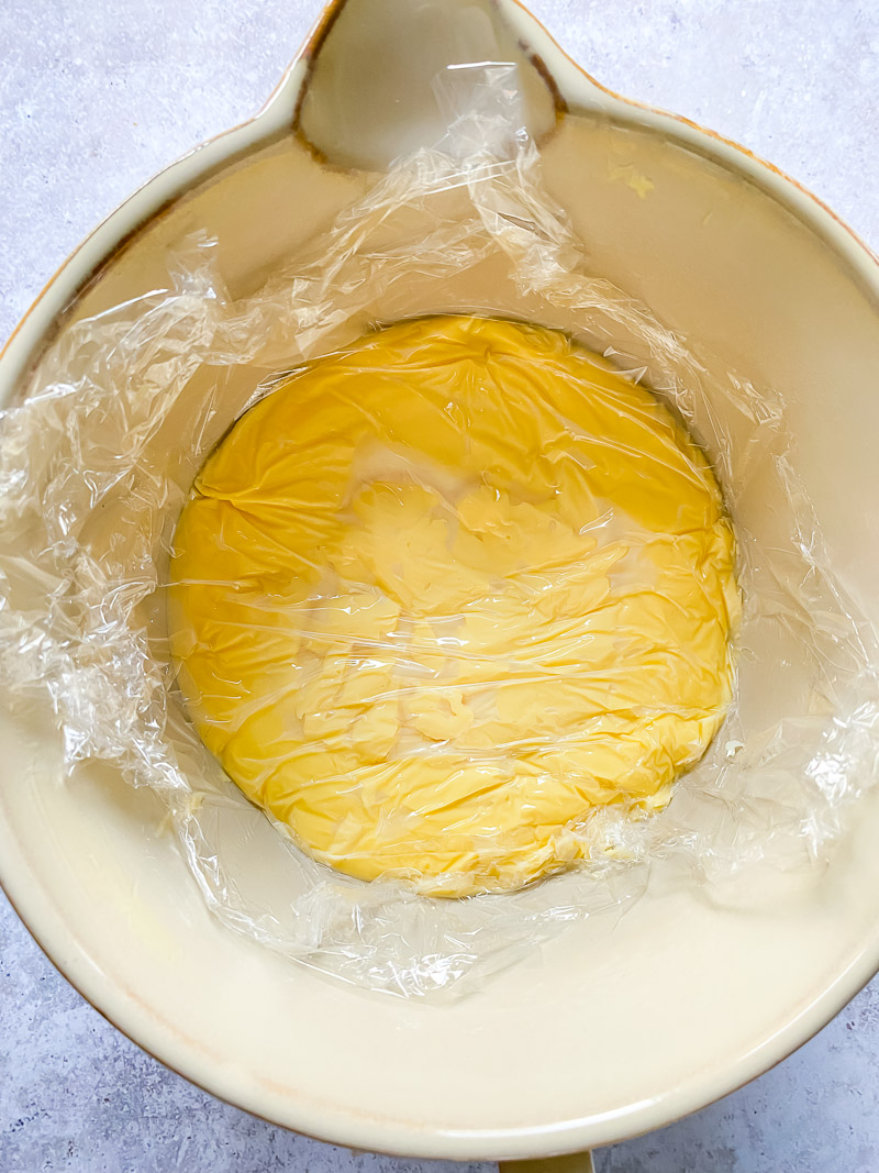 top down view of custard in a bowl with plastic wrap on top